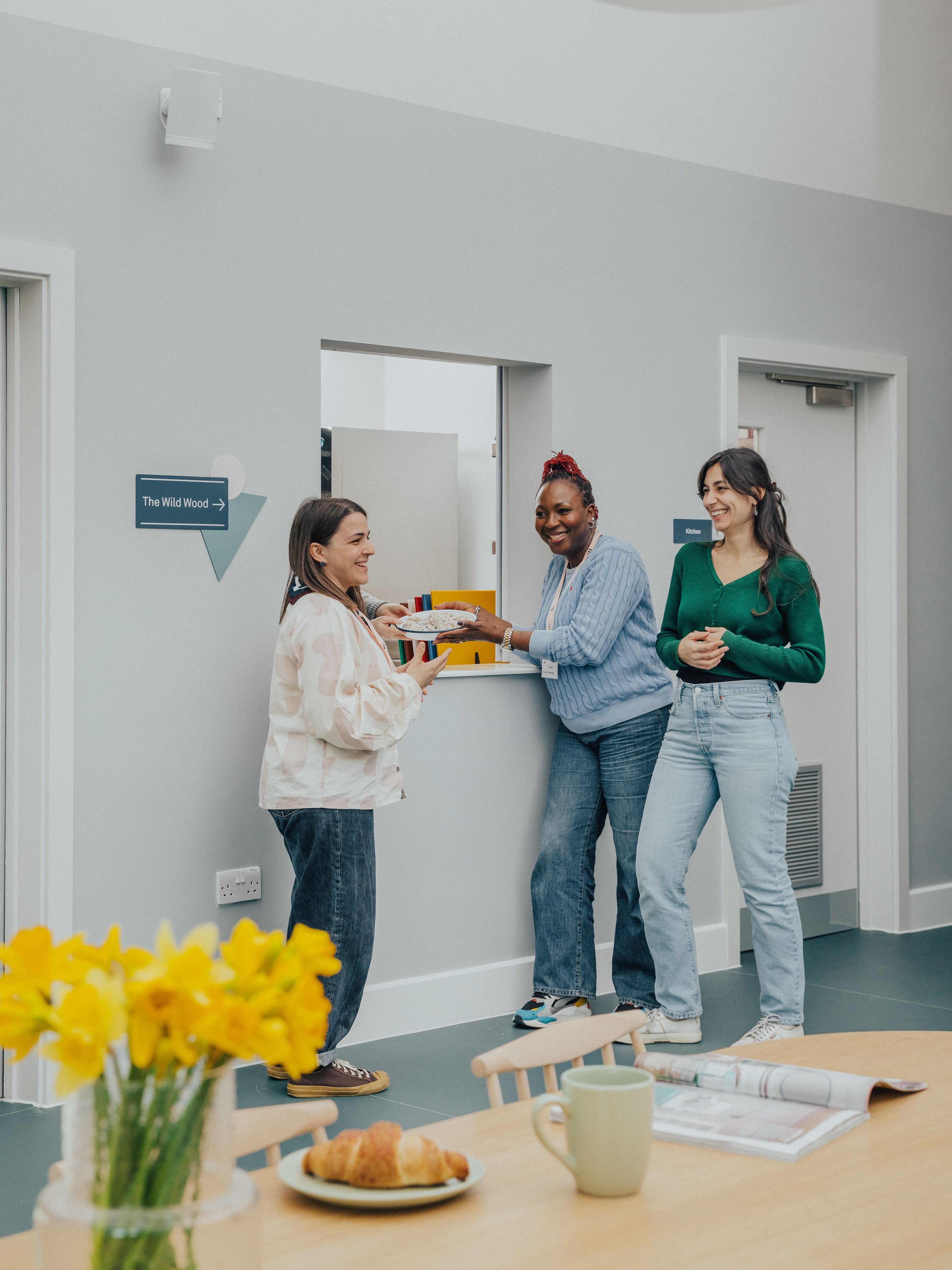 three women are standing in a room with a sign that says the wild wood