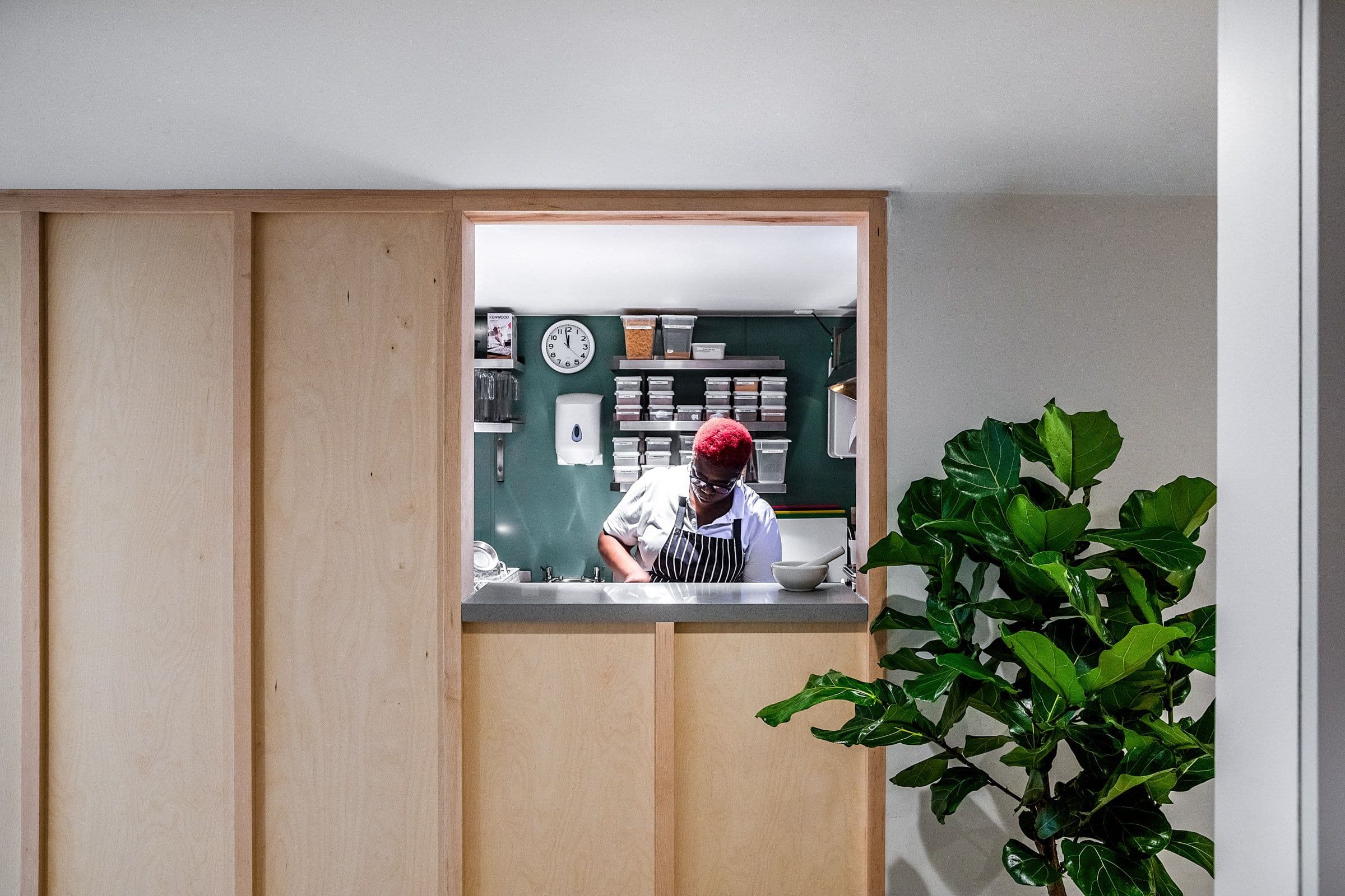 a man in an apron is standing behind a counter in a kitchen .
